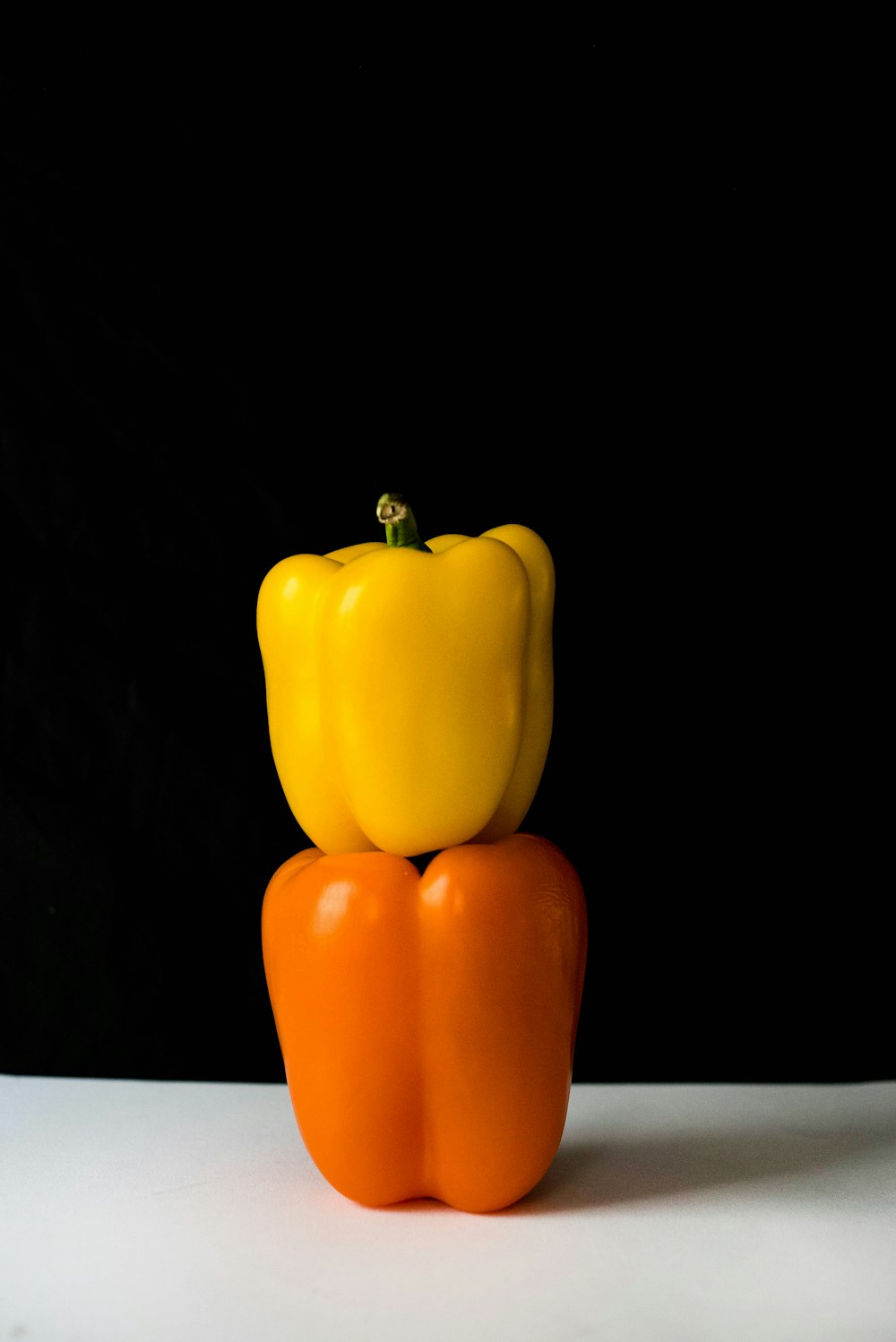 two yellow and orange bell peppers on white surface
