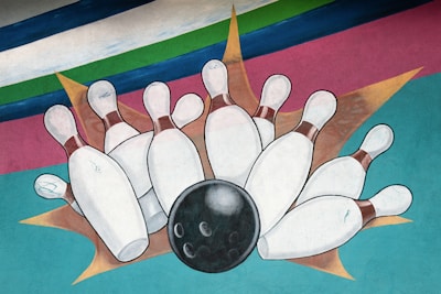 A stylized illustration featuring a black bowling ball striking a set of white bowling pins against a colorful, abstract background with stripes of blue, green, and pink.