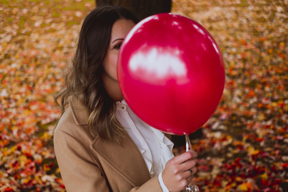 selective focus photography of woman holding red balloon