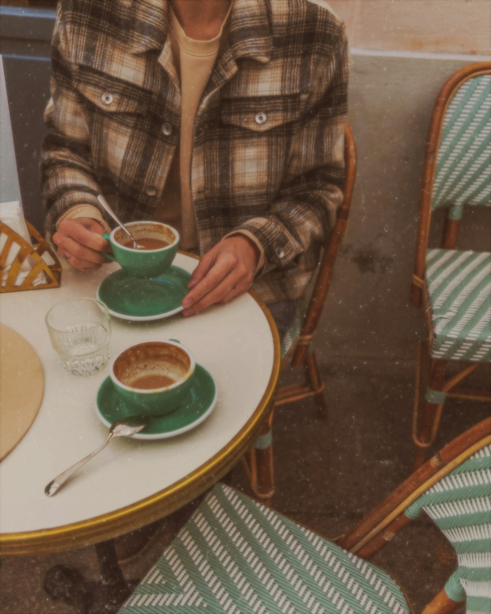 Braun-schwarz kariertes Langarmhemd sitzt neben dem Tisch und hält Teetasse in der Hand