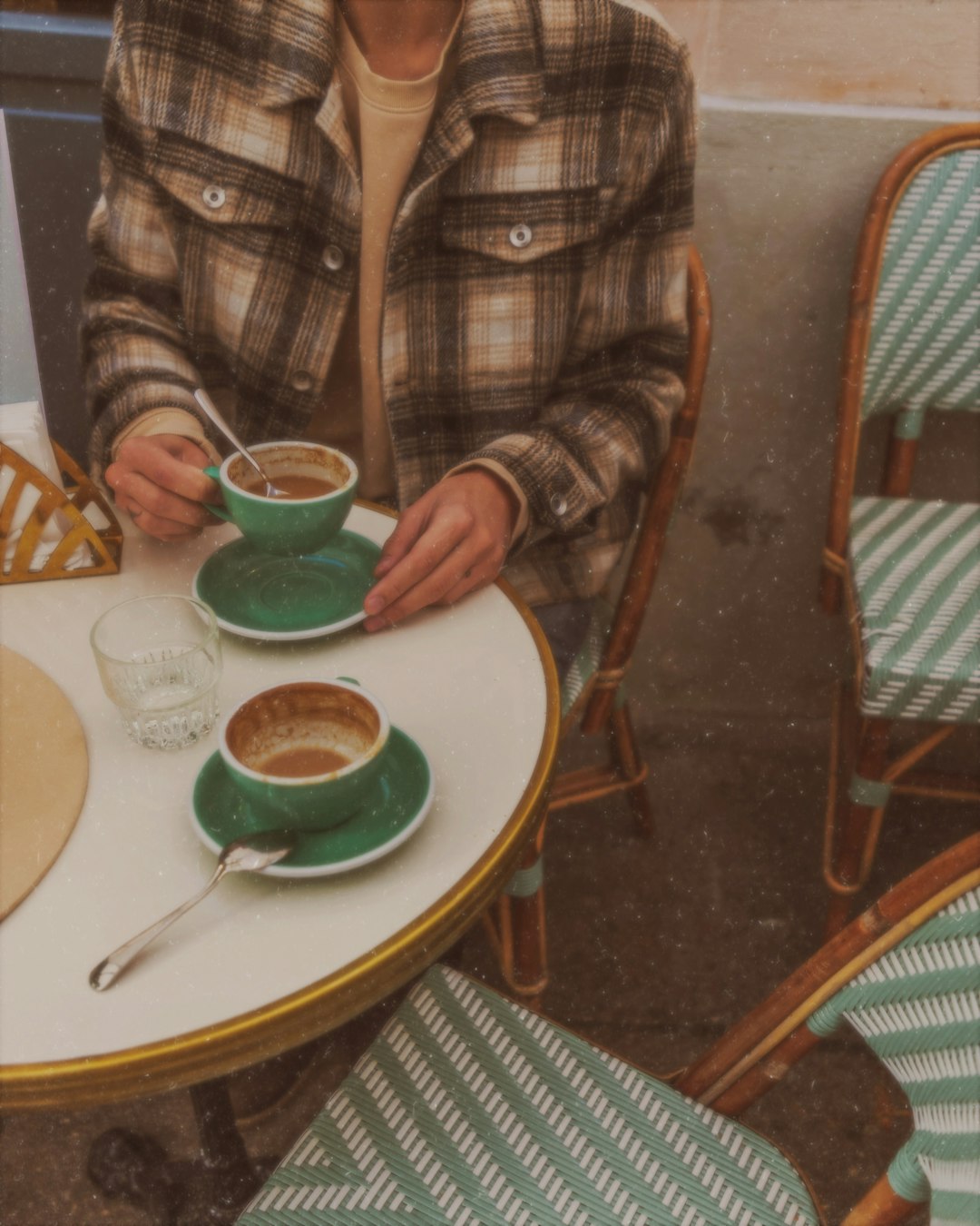 brown and black plaid long-sleeved shirt sitting by the table holding teacup