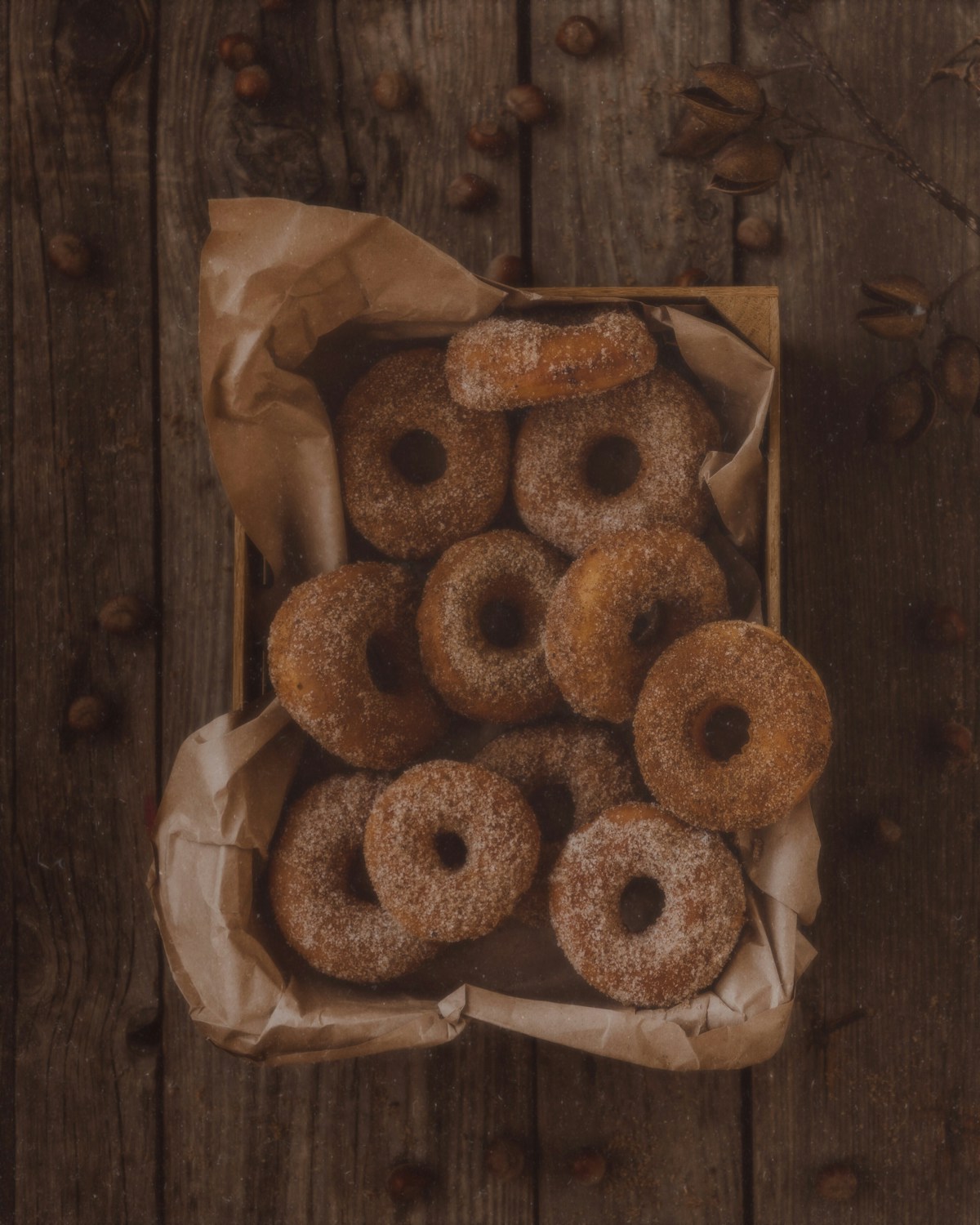 Cinnamon-sugar coated cake donuts in a parchment-lined box on a wooden table