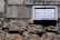 A street sign with the words 'Rua da Ressurreição' is mounted on a textured stone wall. The sign has both Chinese and Portuguese text, with a blue and white color scheme.