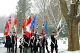 Honor Guard members in uniform presenting flags at a local memorial.