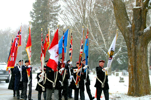 Honor Guard members in uniform presenting flags at a local memorial.