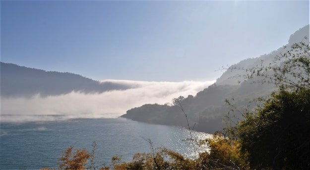 A peaceful sunrise over a serene lake surrounded by gentle hills.