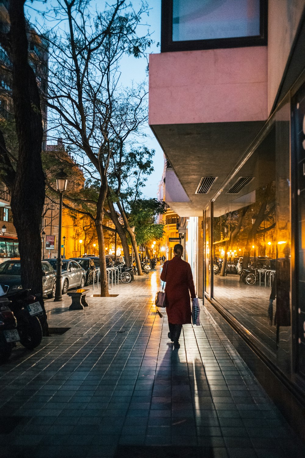 person wearing red trench coat walking on street