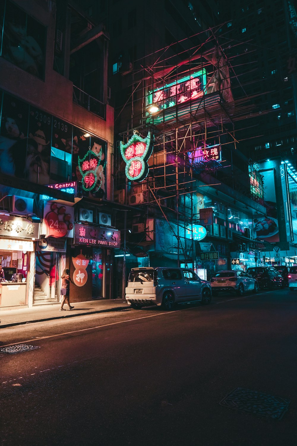 a city street at night with neon signs and scaffolding