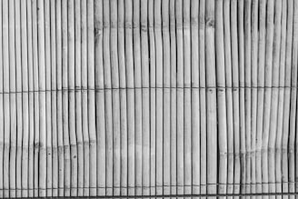 Vertical bamboo sticks are tightly bound together with horizontal black threads, creating a textured and natural pattern.