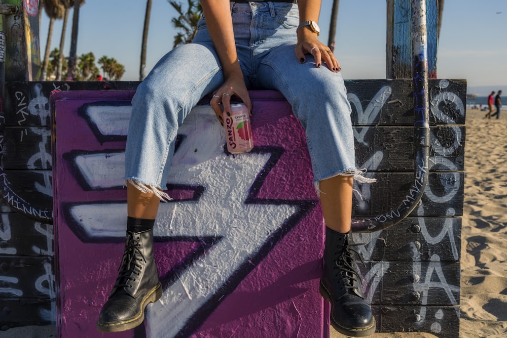 person wearing blue denim jeans holding strawberry soda can