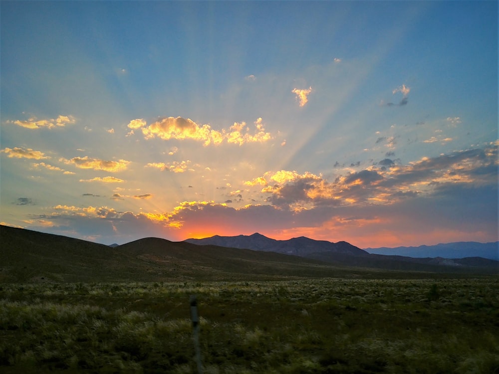 the sun is setting over the mountains in the desert