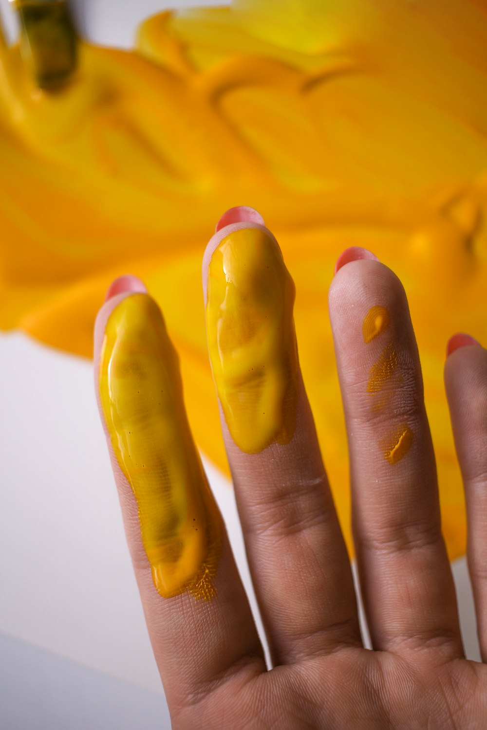 a person's hand with yellow nail polish on it