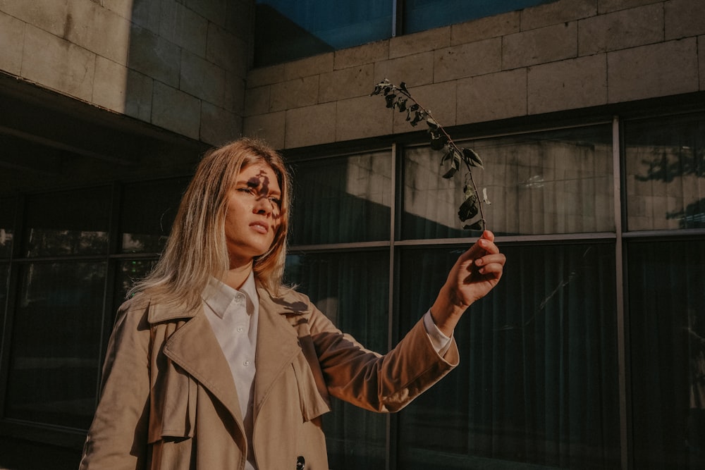 selective focus photography of woman wearing coat holding leaves