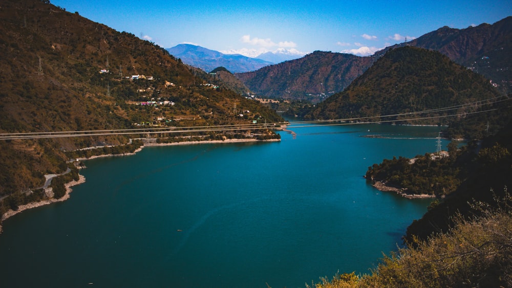 aerial photography of houses on green field viewing mountain and body of water under blue and white sky