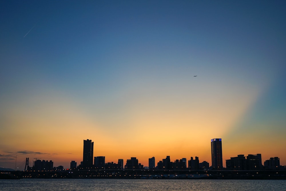 a sunset view of a city with a plane flying in the sky