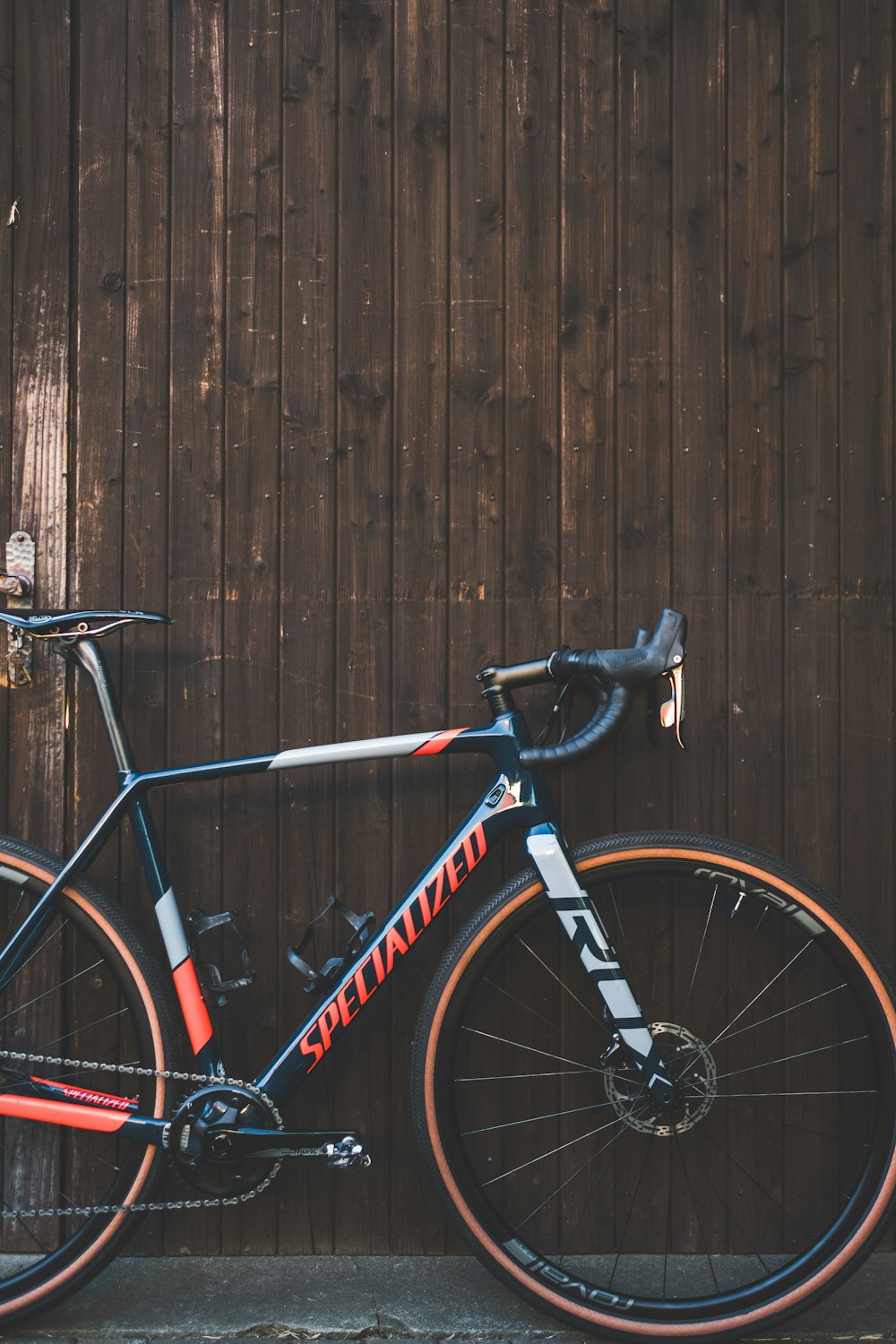 black and orange Specialized road bike parking near brown wall