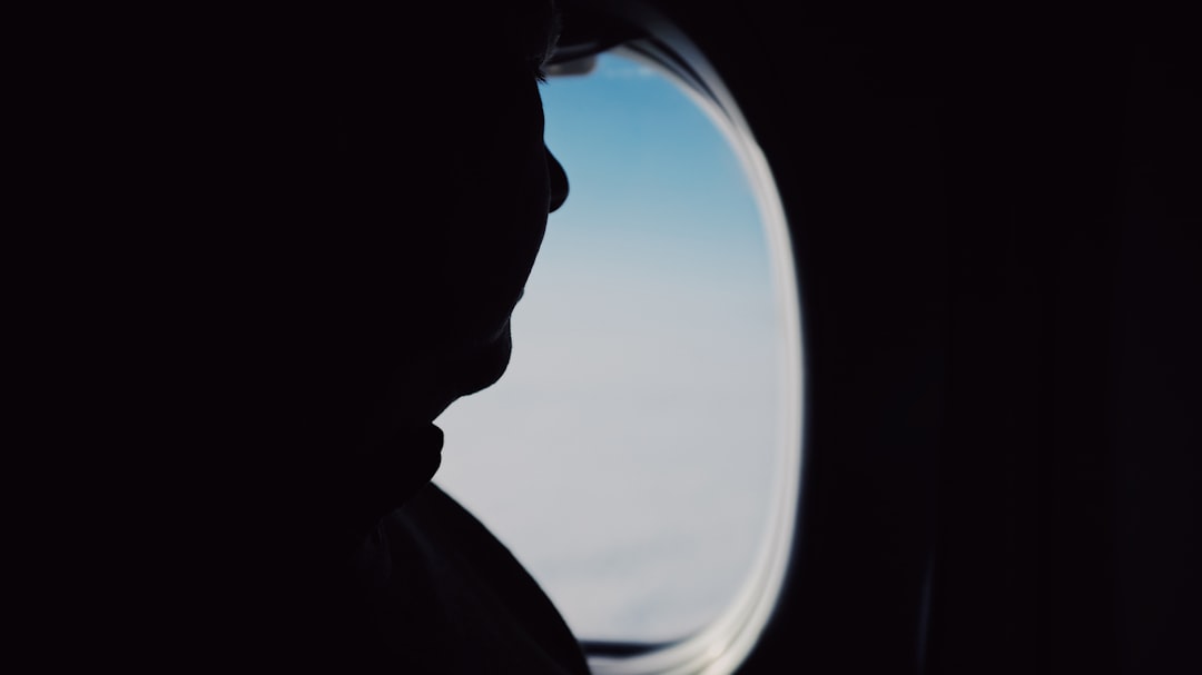 silhouette of person sitting on airplane seat beside window