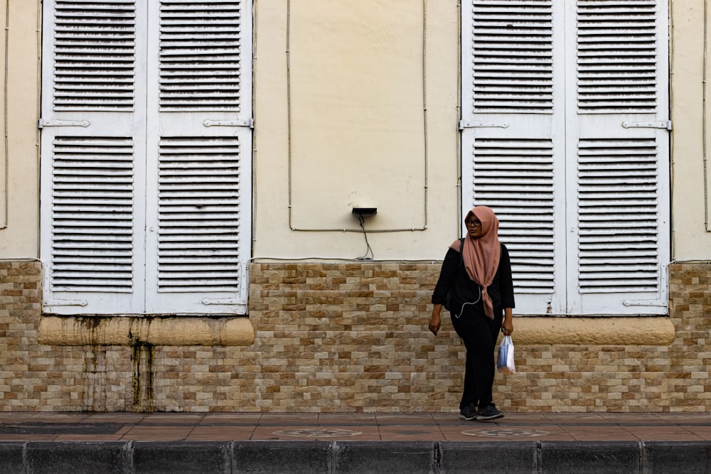 woman wearing beige hijab headscarf standing near building