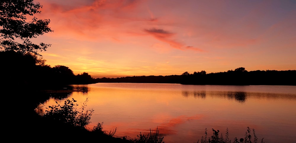 a sunset over a lake with trees and water