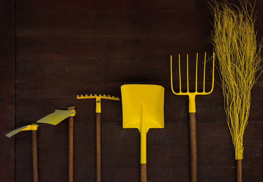 uma fileira de ferramentas de jardim amarelas sentados em cima de um piso de madeira
