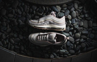 A minimalist shot of Nike sneakers arranged artfully on a white marble surface with subtle gold reflections.