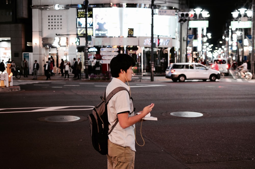 man standing near road wearing earphones