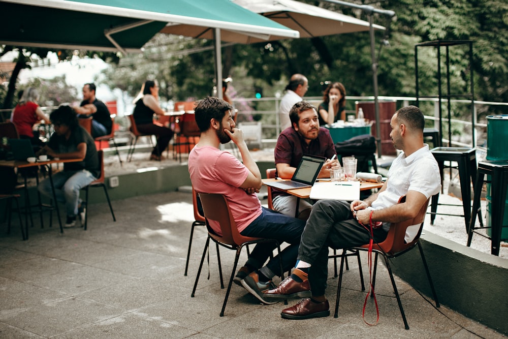 three men sitting beside table