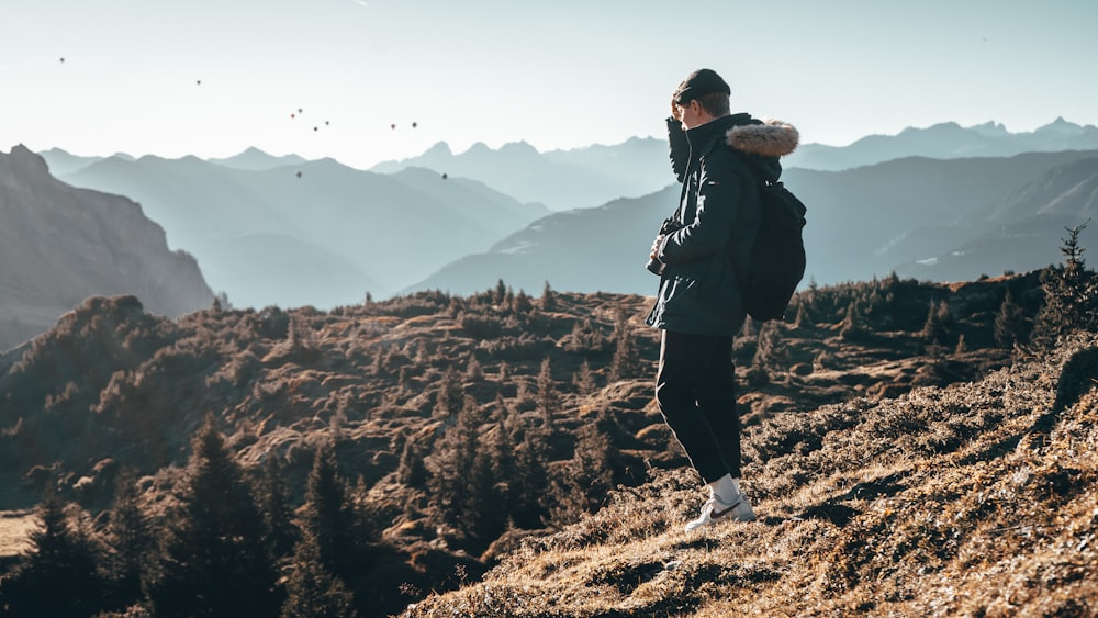 Mann in schwarzer Jacke auf dem Hügel