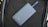 A sleek, matte-finished power bank with the number 5100 on it lies on a textured dark material. A blue strap is attached to the power bank.