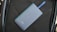 A sleek, matte-finished power bank with the number 5100 on it lies on a textured dark material. A blue strap is attached to the power bank.