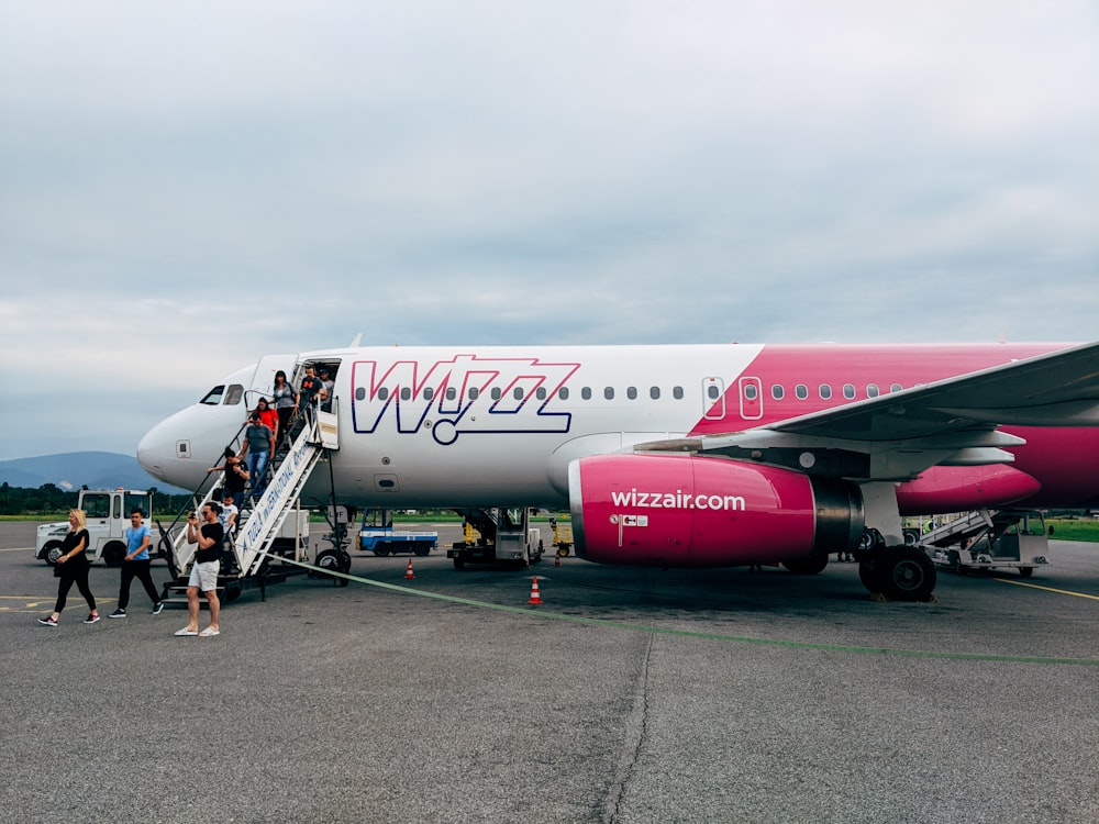 white and pink Wizz Air airliner disembarking passengers