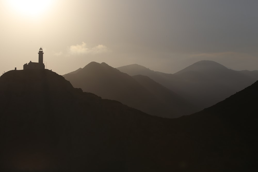silhouette photography of lighthouse on mountain
