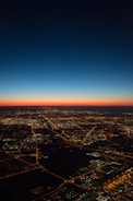 Aerial view of a modern city grid illuminated at dusk with green energy highlights.