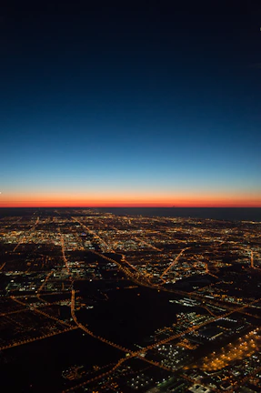 An aerial view of a smart city grid illuminated at dusk, showcasing integrated green spaces and transit routes.