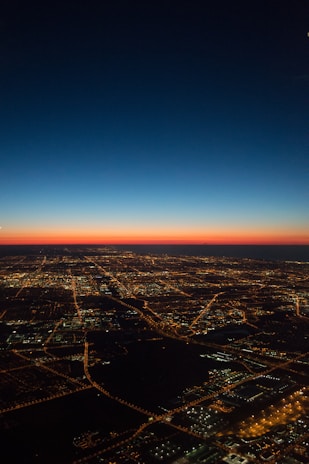 A cinematic aerial shot of a bustling city skyline at sunset with glowing red lights.