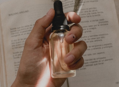 person holding small clear drop bottle