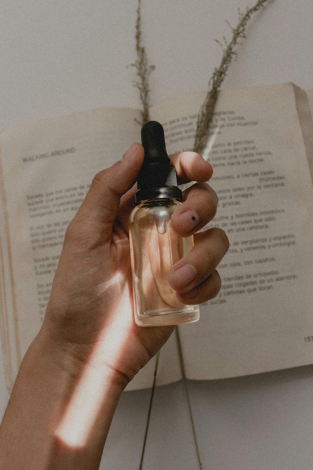 person holding small clear drop bottle