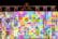 A building facade illuminated with a colorful grid pattern of squares in various hues. The bright projection casts an array of colors across the architectural details, including windows and decorative elements. Flags are visible on the sides, adding to the vibrant ambiance.