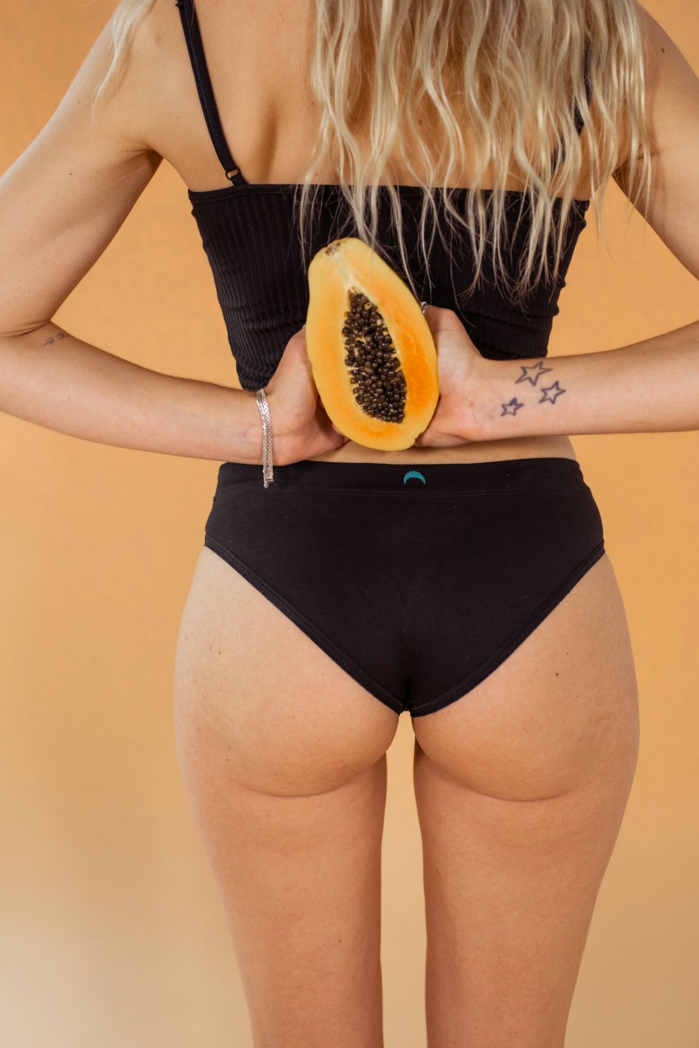 donna in abito nero che tiene la papaya affettata