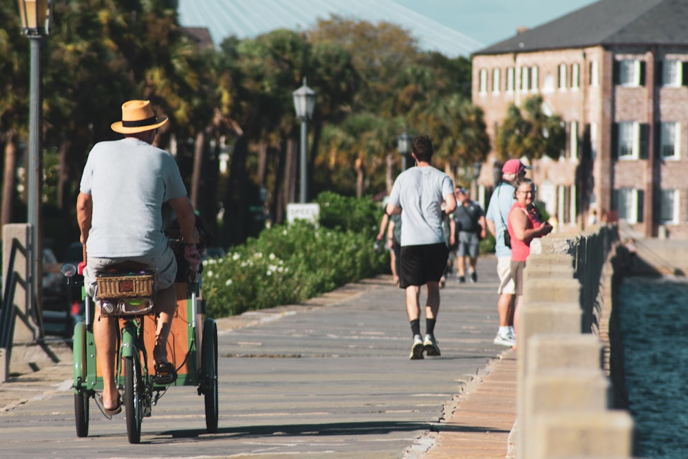 man riding trike near people walking during day