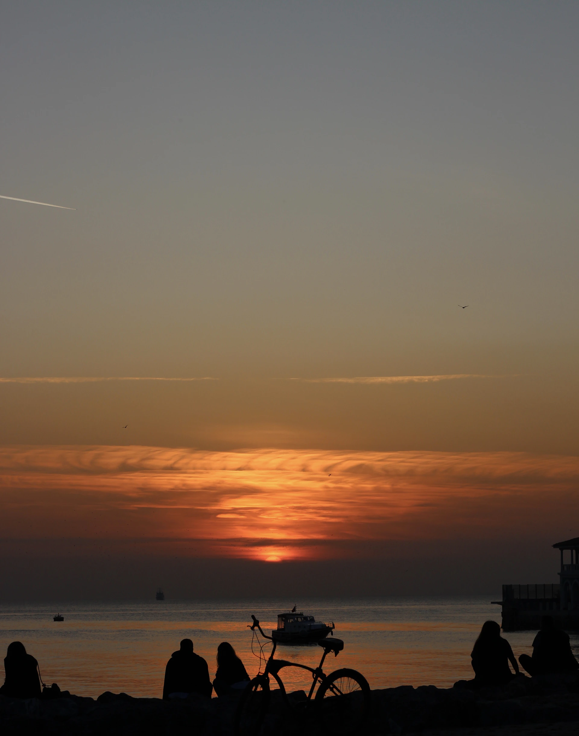 people walking and sitting on beach during sunset