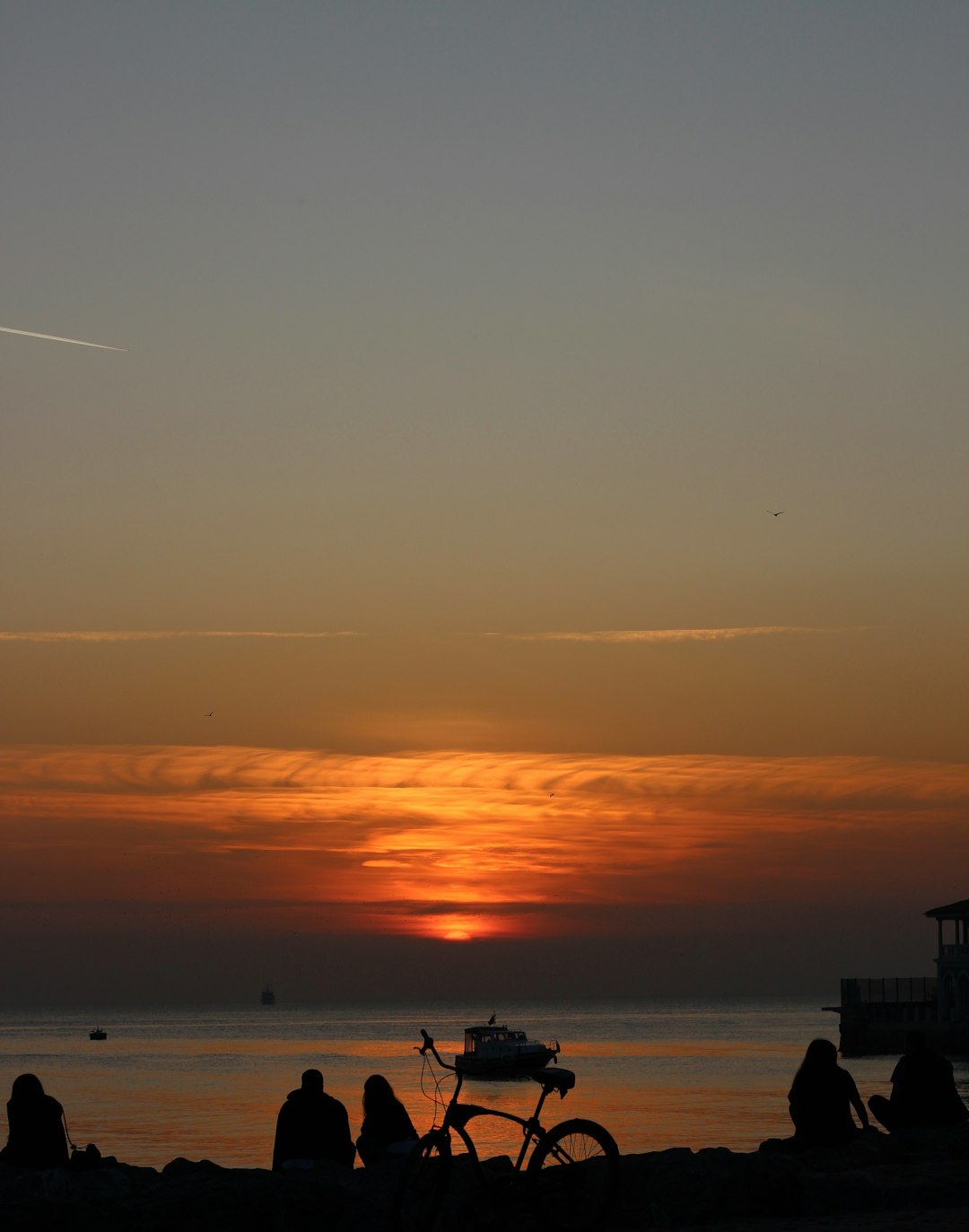 people walking and sitting on beach during sunset