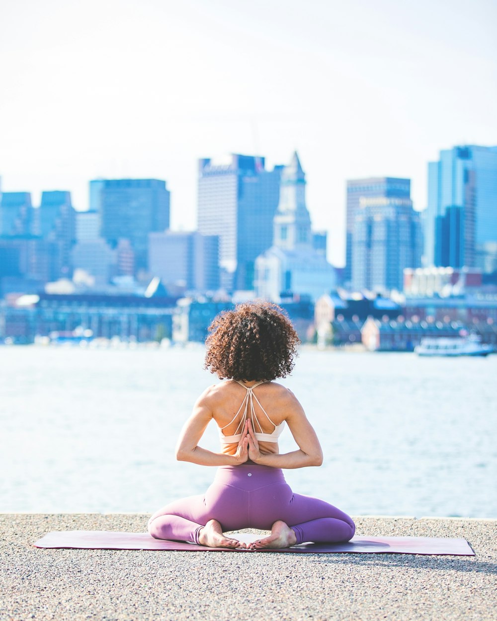 Mujer haciendo yoga frente a un cuerpo de agua tranquilo