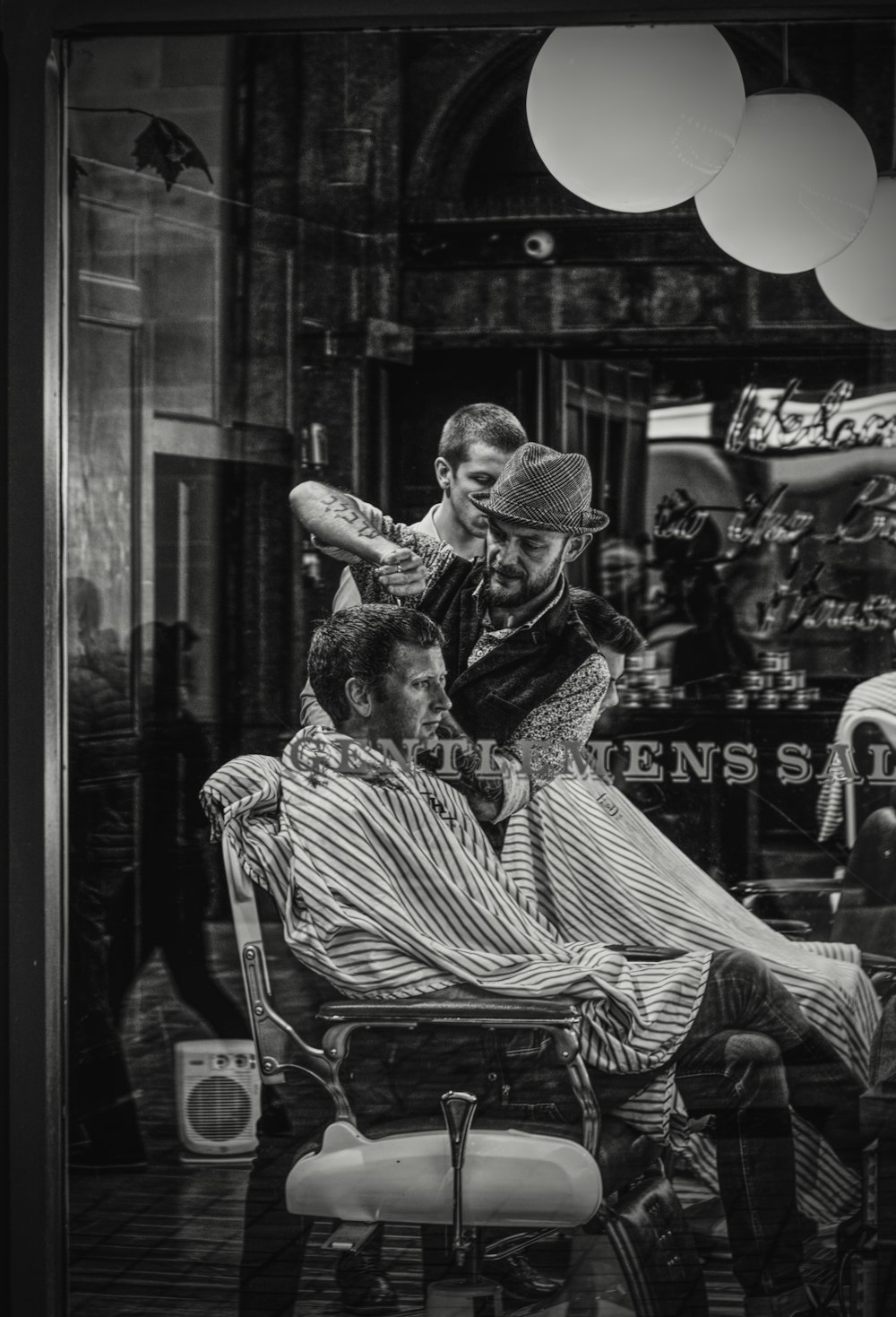 man cutting a person's hair on chair