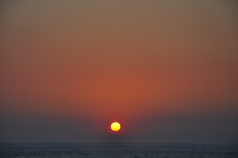 orange sun and body of water