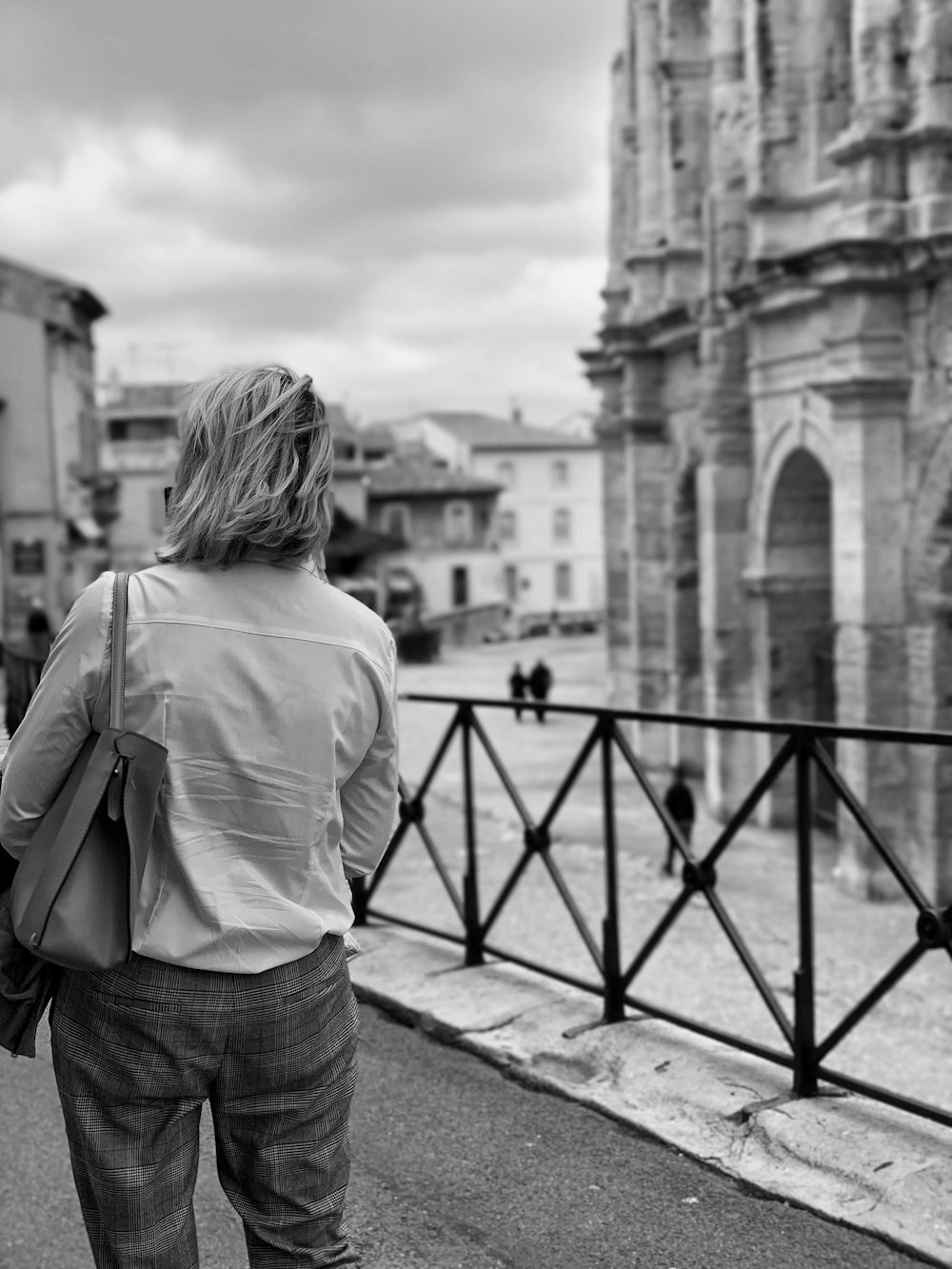 grayscale photography of woman standing near fence