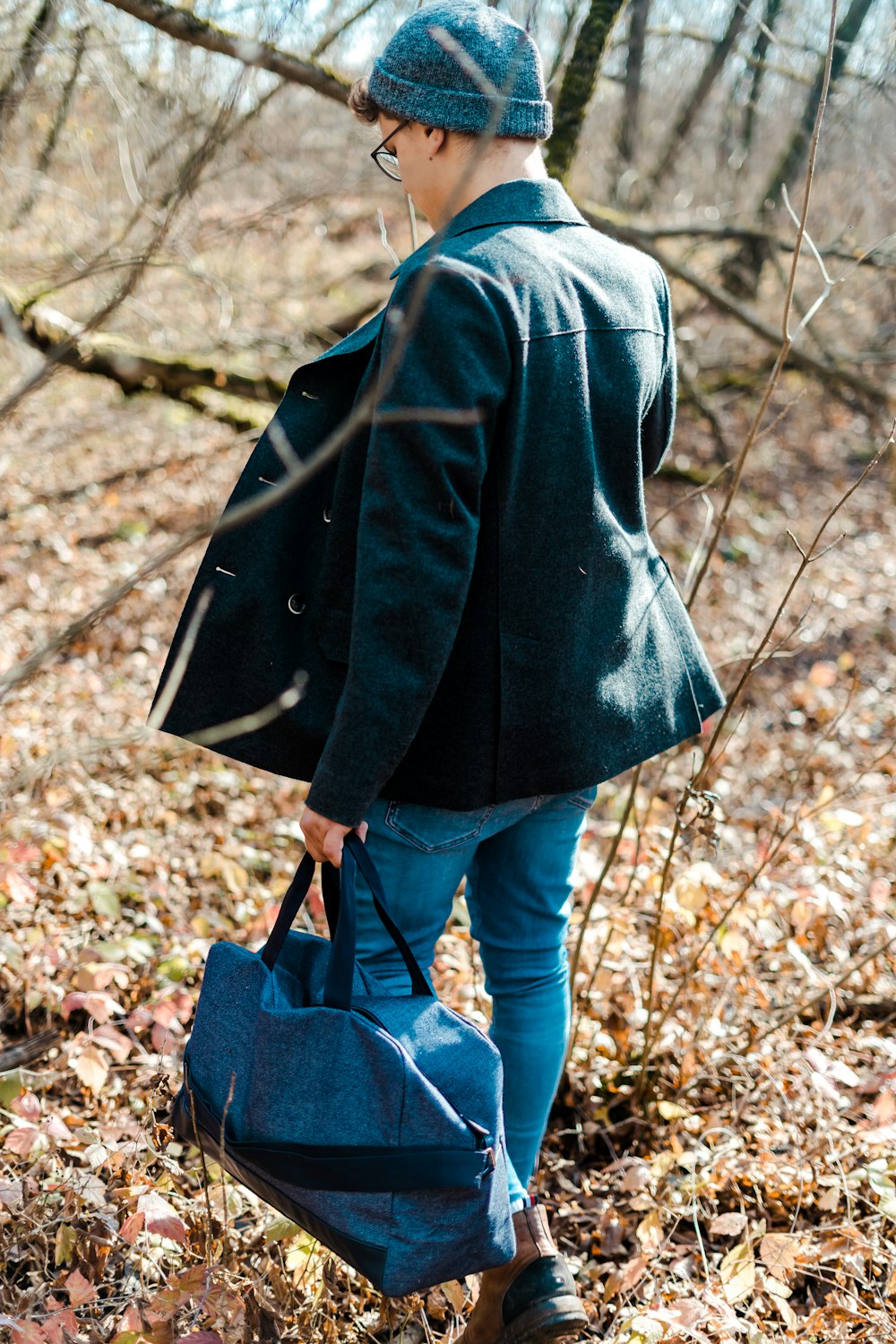 man wearing black leather jacket holding duffel bag