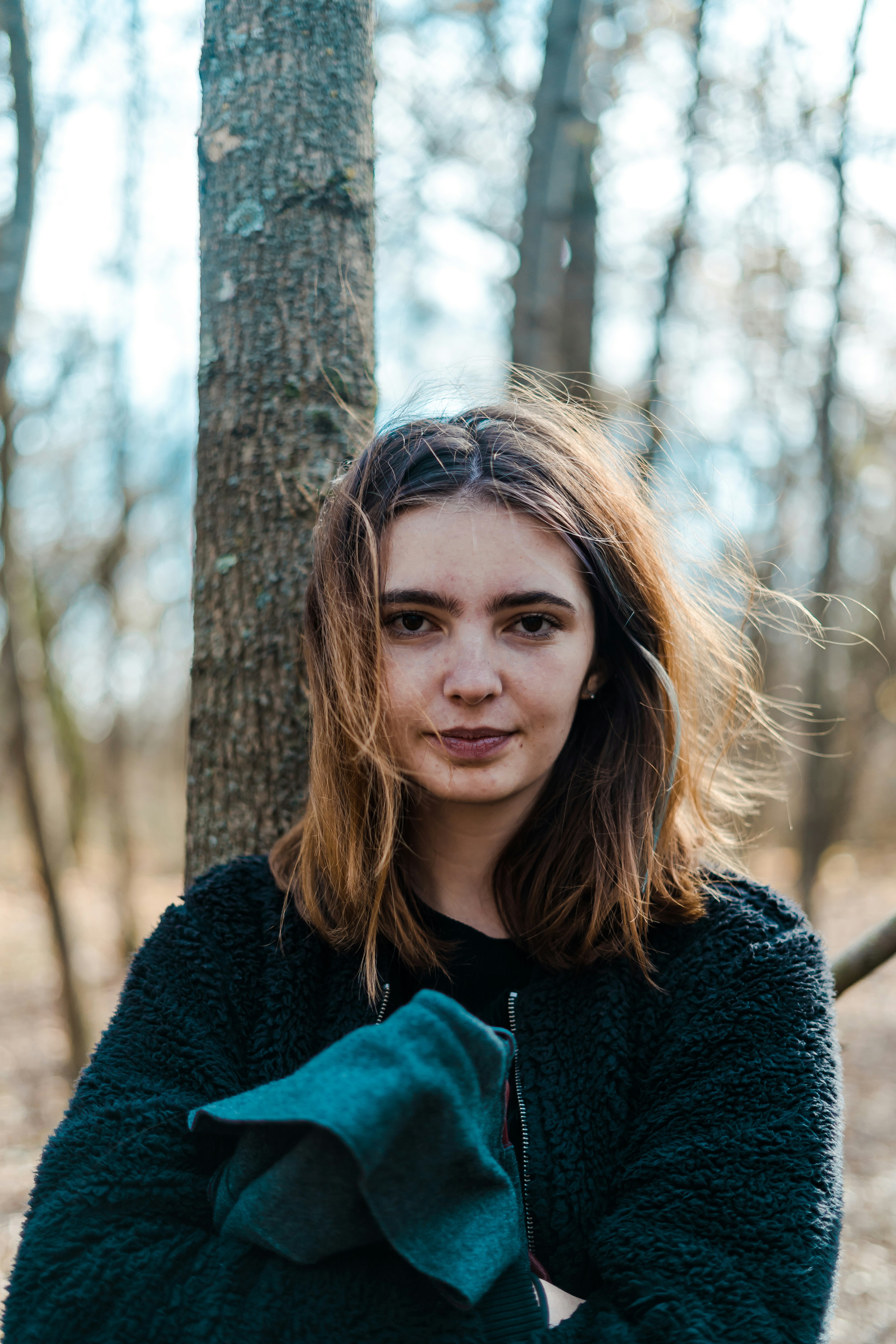 woman in black jacket beside tree