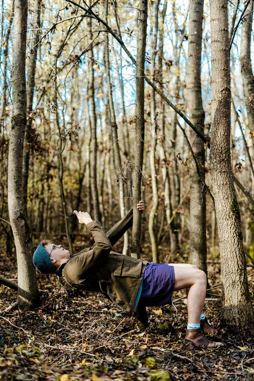 man holding onto tree while lying down