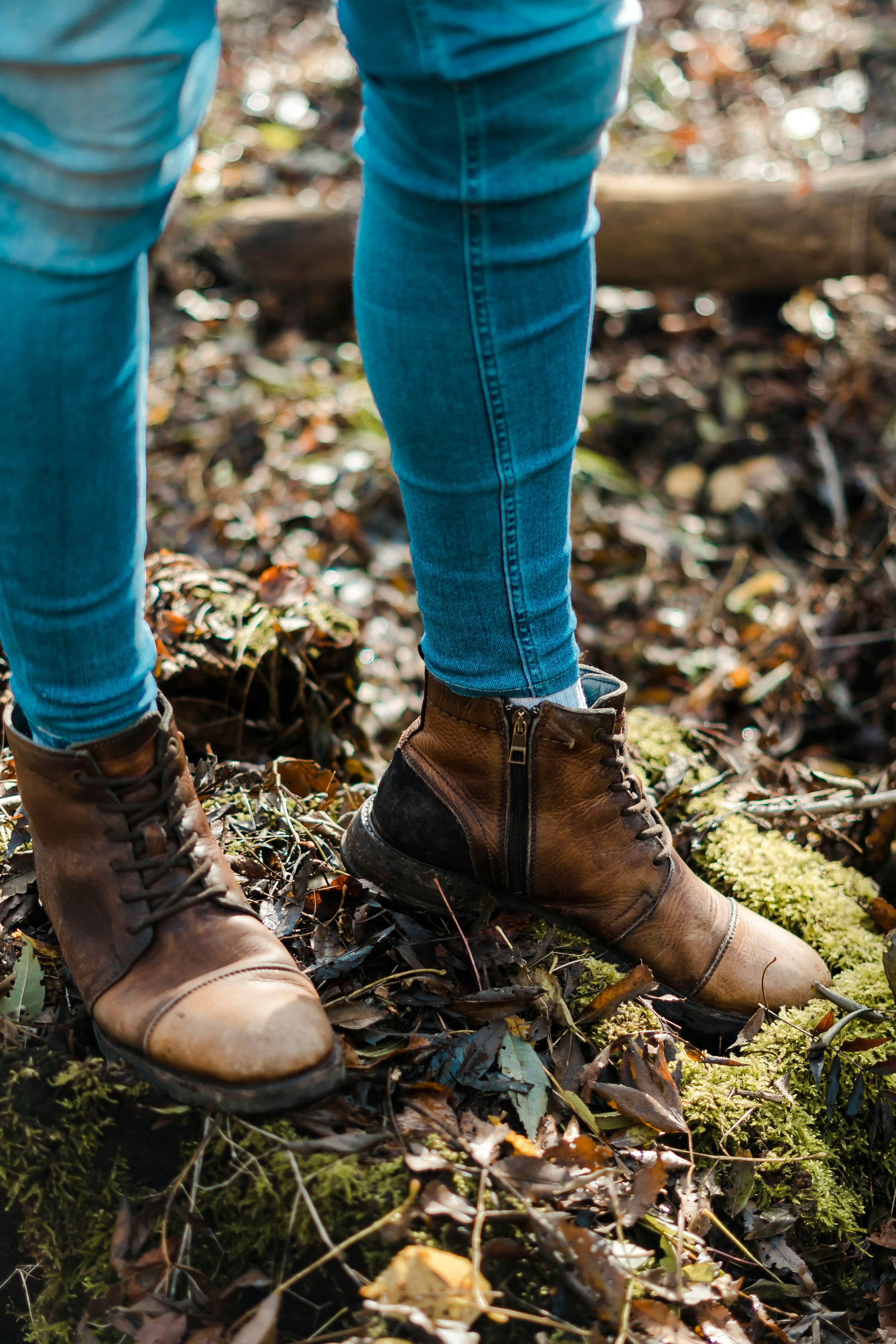 selective focus photography of person wearing blue denim jeans and brown shoes